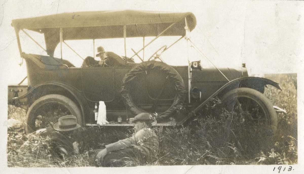 1913 - Men lounging in field near car