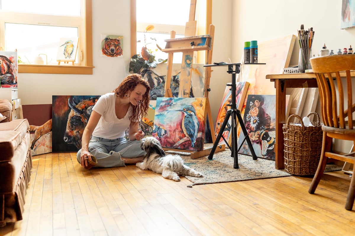 Wildlife Artist Lisa Whitehouse Surrounded by Art and hanging with her dog Luna